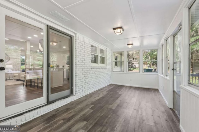 unfurnished sunroom featuring wood finished floors and brick wall