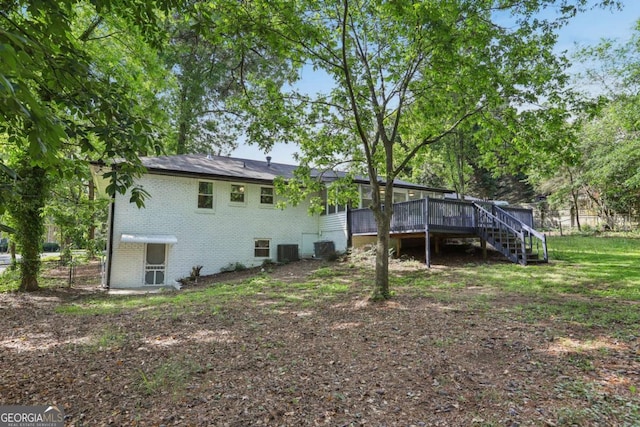 back of property with brick siding, a deck, stairs, fence, and central air condition unit