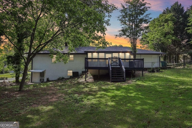 back of house at dusk featuring a wooden deck, a yard, and stairway