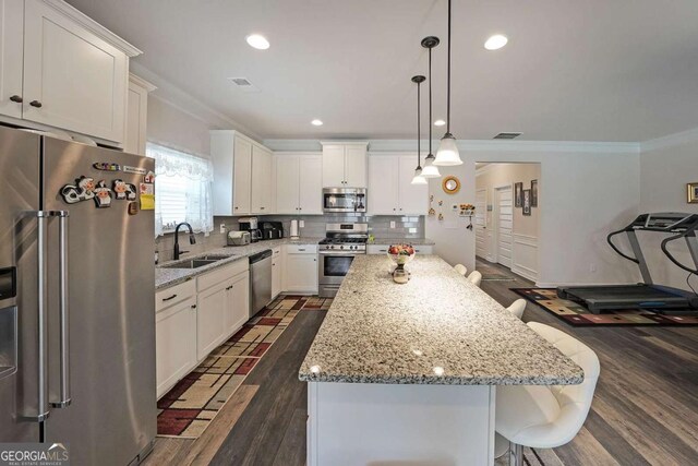 2209 Cedar Place Ct, Snellville, GA 30078 - kitchen featuring appliances with stainless steel finishes, a sink, ornamental molding, dark wood-style flooring, and white cabinetry