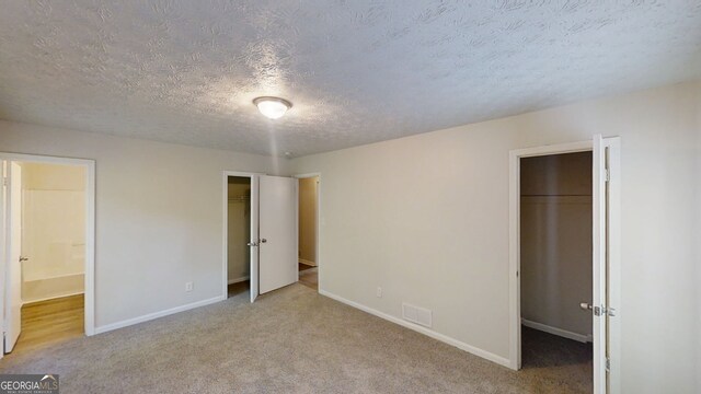 3512 Valley Chase Ct, Lithonia, GA 30038 - unfurnished bedroom featuring carpet flooring, a walk in closet, a textured ceiling, and a closet