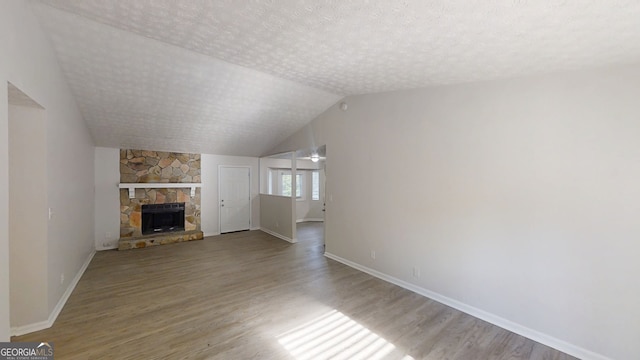 3512 Valley Chase Ct, Lithonia, GA 30038 - unfurnished living room featuring wood finished floors, a stone fireplace, baseboards, lofted ceiling, and a textured ceiling