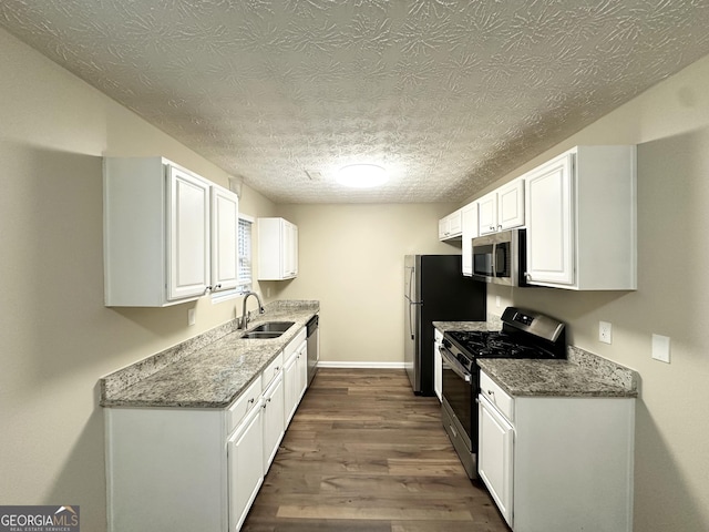 9151 Jefferson Village Dr SW, Covington, GA 30014 - kitchen featuring appliances with stainless steel finishes, a sink, dark wood finished floors, white cabinetry, and light stone countertops