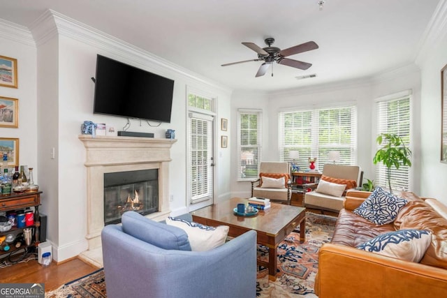 living room featuring ornamental molding, ceiling fan, a premium fireplace, wood finished floors, and baseboards