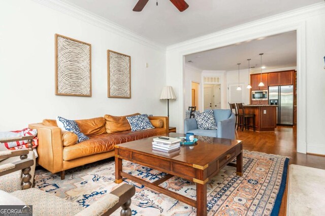 living room with a ceiling fan, crown molding, and wood finished floors