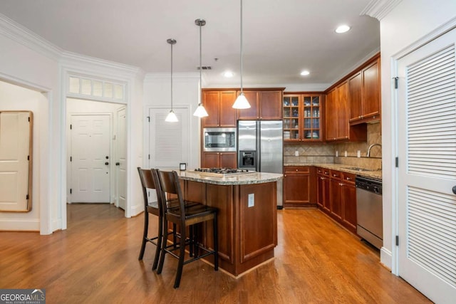 kitchen featuring appliances with stainless steel finishes, a sink, a kitchen island, decorative backsplash, and a kitchen breakfast bar