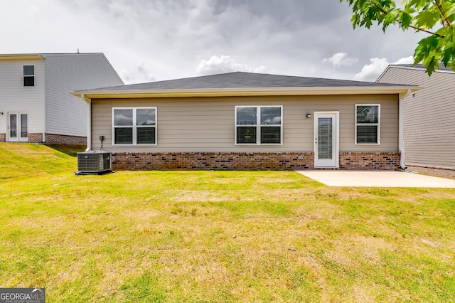 rear view of property featuring brick siding, a patio, a lawn, and central AC unit