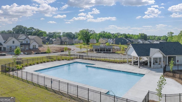 community pool featuring a residential view, fence, and a patio