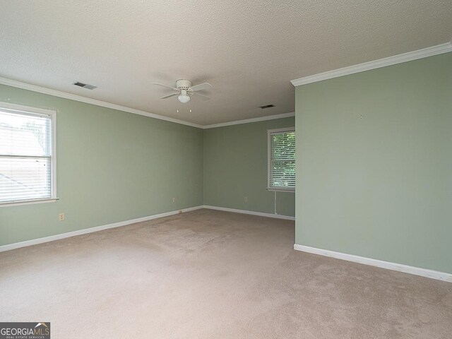 spare room with a ceiling fan, light colored carpet, crown molding, baseboards, and a textured ceiling