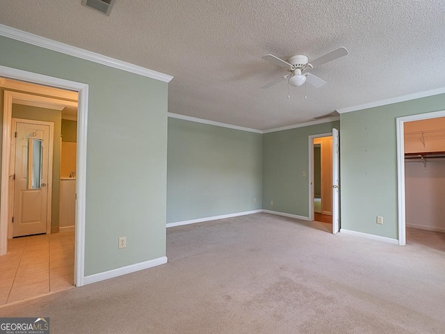 unfurnished bedroom featuring a spacious closet, carpet flooring, ornamental molding, baseboards, and a textured ceiling