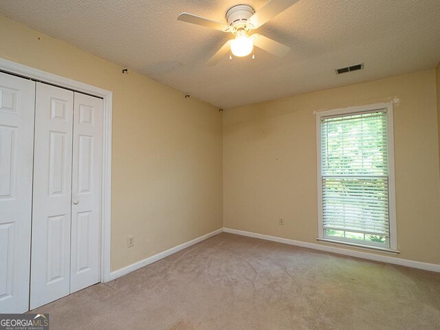 unfurnished bedroom featuring carpet, a textured ceiling, multiple windows, a closet, and baseboards