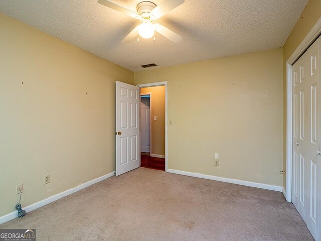 unfurnished bedroom with carpet floors, baseboards, a textured ceiling, and a closet