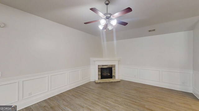 900 Ellesmere Pt, Mcdonough, GA 30253 - unfurnished living room with a fireplace, a ceiling fan, light wood finished floors, a wainscoted wall, and a decorative wall