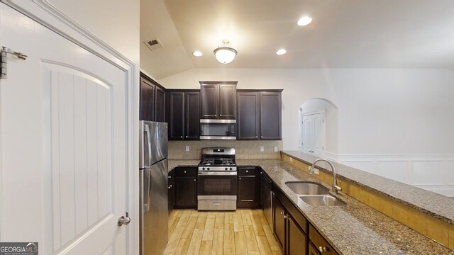 900 Ellesmere Pt, Mcdonough, GA 30253 - kitchen featuring stainless steel appliances, tasteful backsplash, light stone countertops, arched walkways, and light wood-style flooring