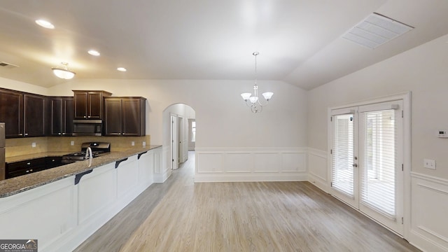 900 Ellesmere Pt, Mcdonough, GA 30253 - kitchen with appliances with stainless steel finishes, arched walkways, vaulted ceiling, light stone countertops, and light wood-type flooring