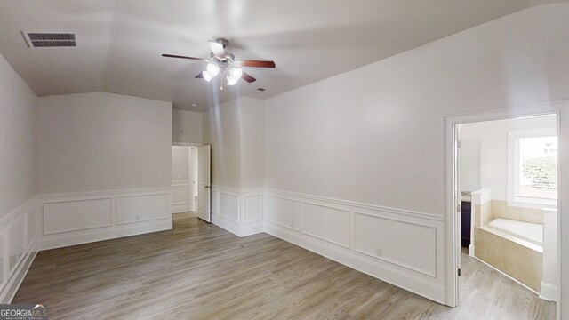 900 Ellesmere Pt, Mcdonough, GA 30253 - unfurnished room featuring ceiling fan, light wood-type flooring, vaulted ceiling, a wainscoted wall, and a decorative wall