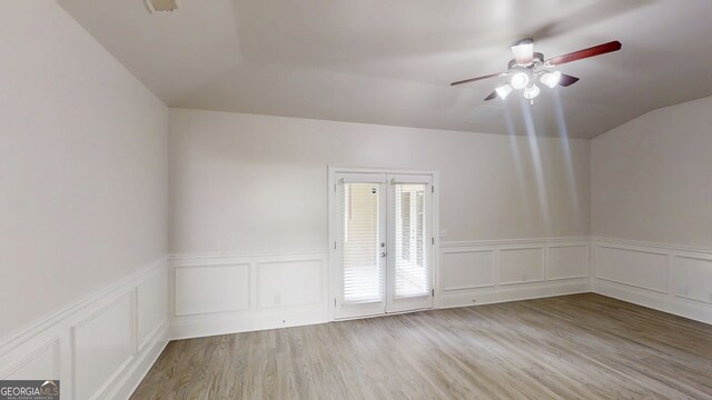 900 Ellesmere Pt, Mcdonough, GA 30253 - unfurnished room featuring a ceiling fan, light wood-style floors, vaulted ceiling, wainscoting, and a decorative wall