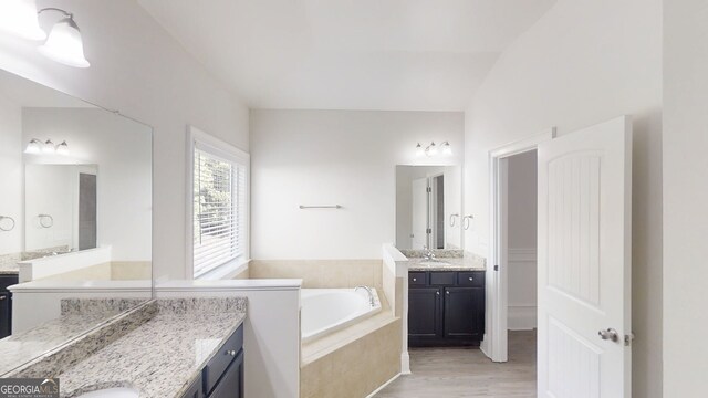 900 Ellesmere Pt, Mcdonough, GA 30253 - bathroom featuring a garden tub, two vanities, and wood finished floors