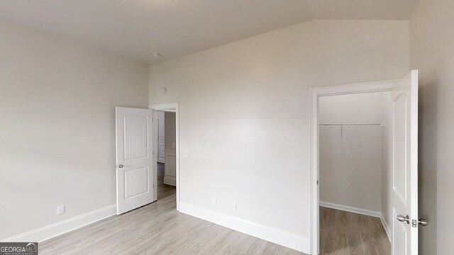 900 Ellesmere Pt, Mcdonough, GA 30253 - unfurnished bedroom with light wood-style floors, lofted ceiling, baseboards, a closet, and a spacious closet