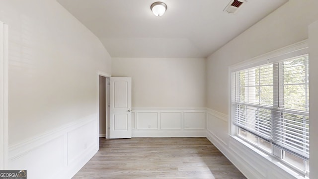 900 Ellesmere Pt, Mcdonough, GA 30253 - empty room with vaulted ceiling, a wainscoted wall, a decorative wall, and light wood finished floors