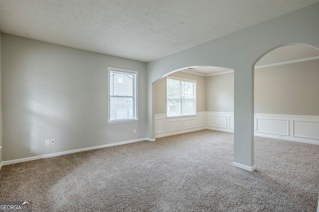 8826 Lakecrest Way, Union City, GA 30291 - unfurnished room featuring carpet flooring, a wainscoted wall, a textured ceiling, ornamental molding, and arched walkways