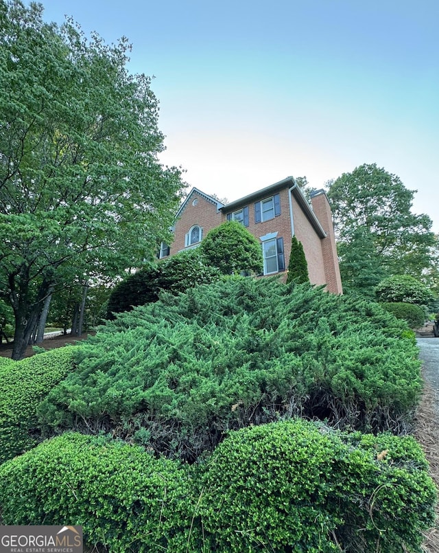 view of side of home with a chimney and brick siding