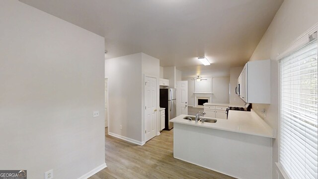 4912 Lightwood Ct NW, Acworth, GA 30102 - kitchen featuring a peninsula, freestanding refrigerator, light wood-style floors, baseboards, and white cabinets
