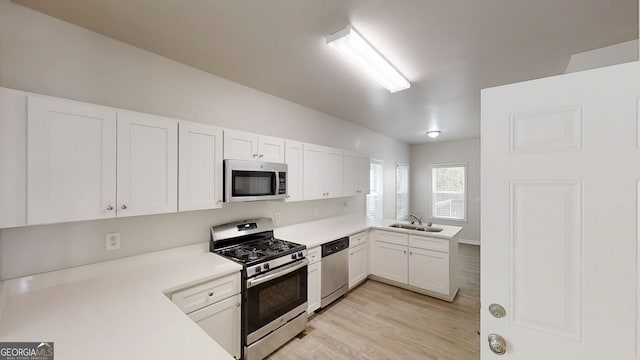 4912 Lightwood Ct NW, Acworth, GA 30102 - kitchen featuring stainless steel appliances, a sink, light countertops, light wood-type flooring, and white cabinetry