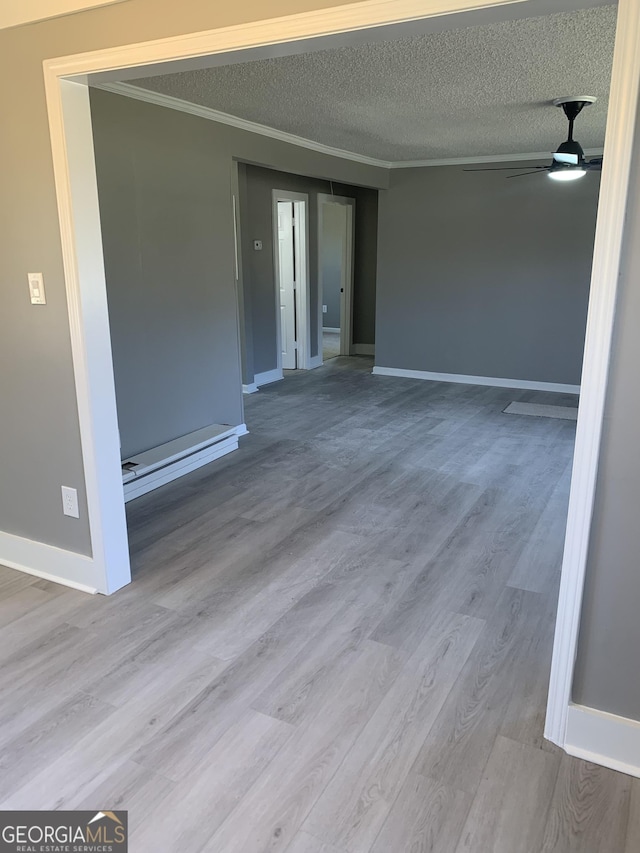 unfurnished room featuring ornamental molding, wood finished floors, baseboards, ceiling fan, and a textured ceiling