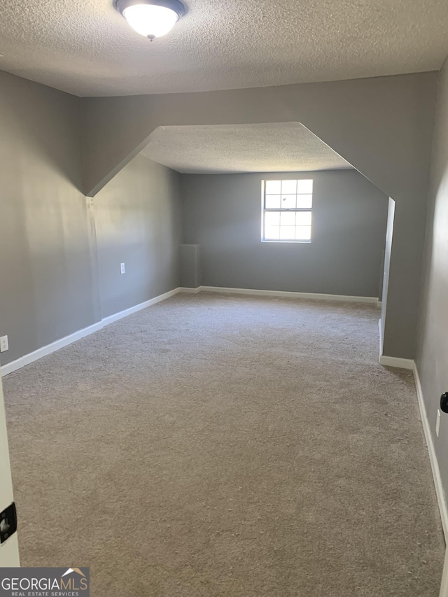 bonus room featuring a textured ceiling, carpet, and baseboards