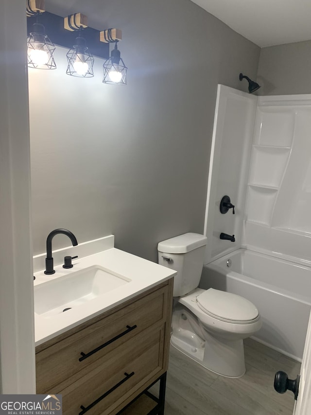 full bathroom featuring toilet, wood finished floors, vanity, and tub / shower combination