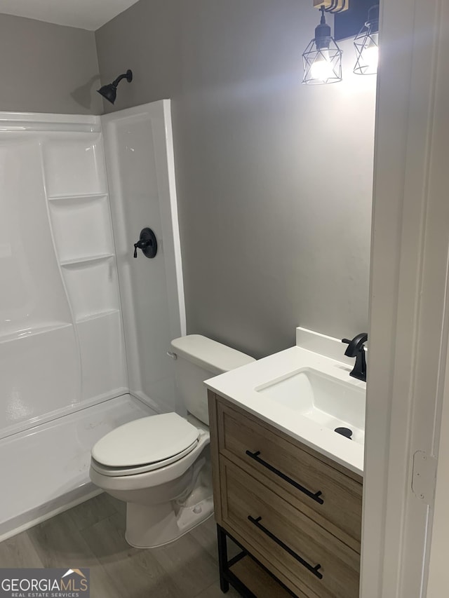 bathroom with a shower stall, toilet, and vanity