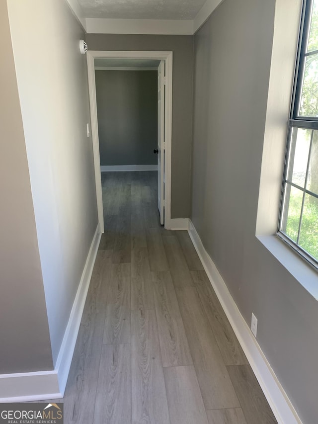 corridor featuring wood finished floors and baseboards