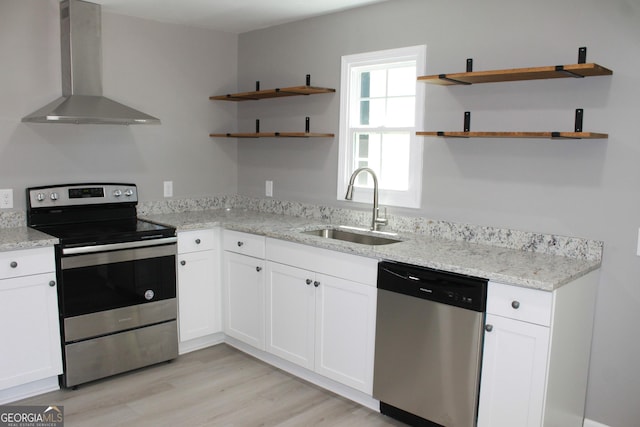 kitchen with appliances with stainless steel finishes, wall chimney exhaust hood, open shelves, and a sink