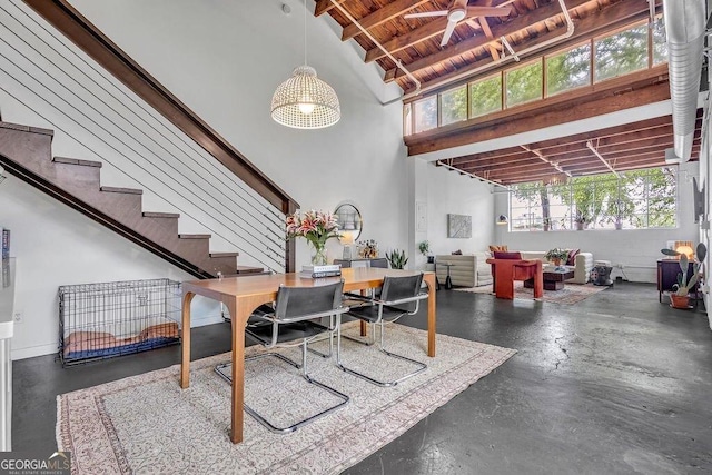 dining area with a towering ceiling, plenty of natural light, ceiling fan, wood ceiling, and finished concrete flooring
