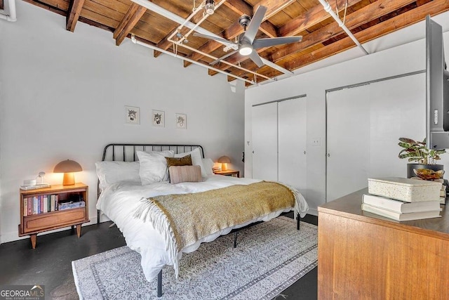 bedroom featuring wood ceiling, beam ceiling, two closets, and ceiling fan