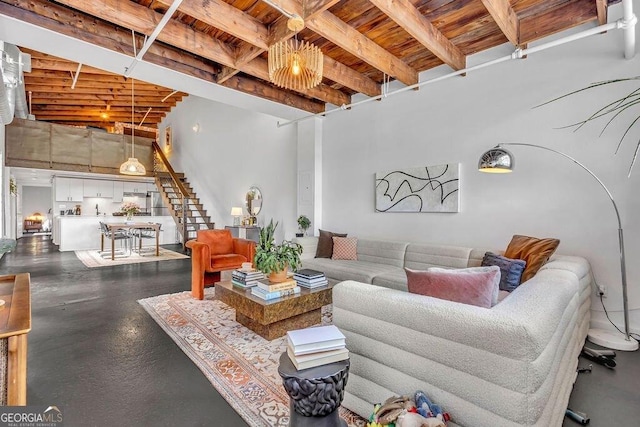living area featuring stairs, wooden ceiling, beam ceiling, and a towering ceiling