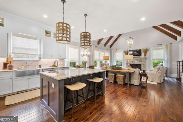 kitchen with a sink, open floor plan, an island with sink, light stone countertops, and recessed lighting