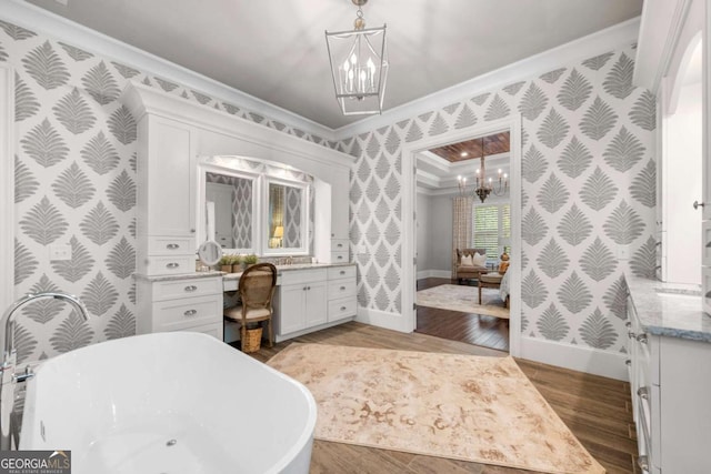 bathroom with wallpapered walls, ornamental molding, a chandelier, vanity, and baseboards