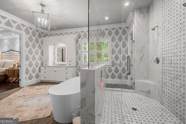 bathroom featuring ornamental molding, wood finished floors, a stall shower, ensuite bath, and vanity