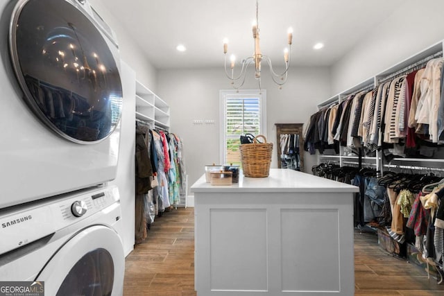 spacious closet with stacked washer / drying machine, dark wood finished floors, and a chandelier