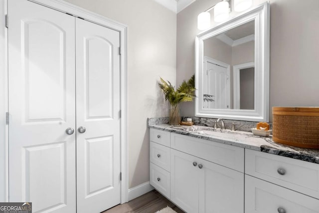 bathroom featuring vanity, ornamental molding, baseboards, and wood finished floors