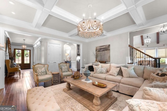 living area featuring a chandelier, coffered ceiling, hardwood / wood-style flooring, plenty of natural light, and arched walkways