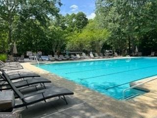 community pool featuring a patio and view of wooded area