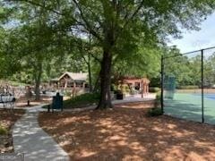 view of home's community featuring a tennis court and fence