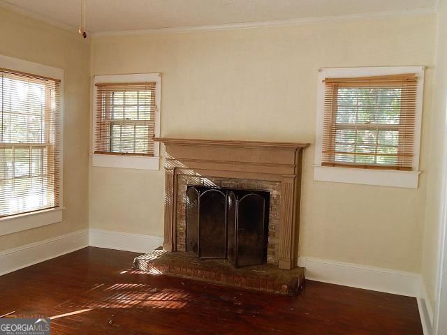detailed view of ornamental molding, wood finished floors, baseboards, and a fireplace with raised hearth