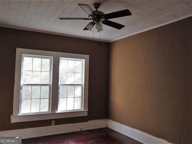 empty room featuring plenty of natural light, ornamental molding, baseboards, and ceiling fan