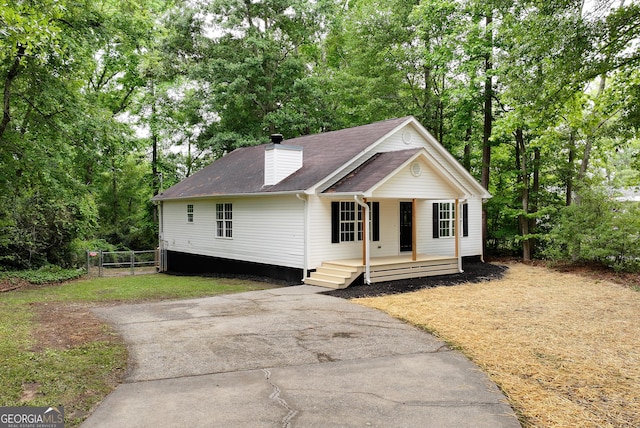 235 Baugh St, Commerce, GA 30529 - view of front of home with covered porch, a chimney, fence, a shingled roof, and view of wooded area