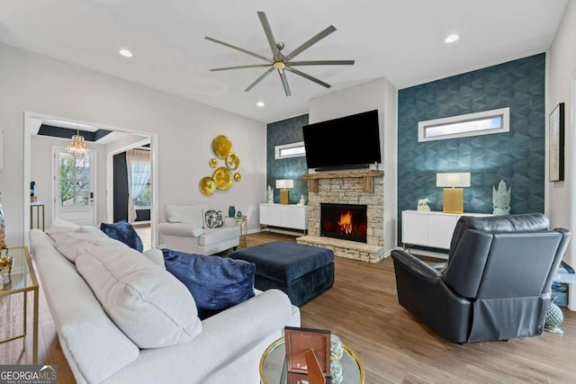 438 Southland Cir, Canton, GA 30115 - living room with an accent wall, a ceiling fan, a chandelier, a stone fireplace, and wood finished floors