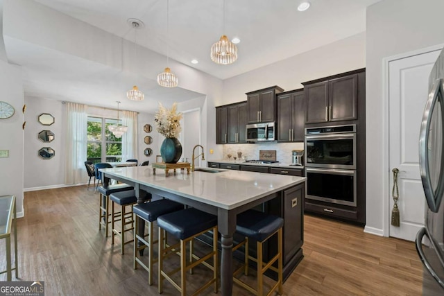 438 Southland Cir, Canton, GA 30115 - kitchen featuring stainless steel appliances, a sink, a breakfast bar area, dark brown cabinetry, and a chandelier